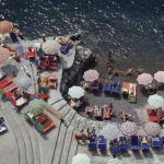 Elevated view looking down on sunbathers and parasols on the beach at La Scogliera beach in Positano, Italy, 1979.