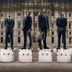 Éder Militão, Daniel Carvajal, Kylian Mbappé, Jude Bellingham, Vinicius Júnior and Thibaut Courtois standing on Louis Vuitton trunks, wearing the LV x Real Madrid formal wear collection.
