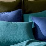 six pillows resting on a bed, enveloped by pillowcases in earthy and blue tones