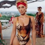 kim kardashian standing in a tiger-printed swimsuit with a red hairband, in front of two women and a dog outside
