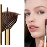 Hourglass tubing mascara in brown with swatch; woman testing Hourglass mascara in brown