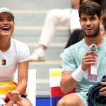 The doubles team of Emma Raducanu of Great Britain and Carlos Alcaraz of Spain share a laugh as they sit on the bench in between games durin
