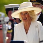 Queen Camilla wears white Dior dress and British bugle horn brooch for VJ Day celebration.