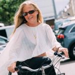 Female on bicycle wearing white sheer pleated shirt and sunglasses at Copenhagen Spring 2026 Fashion Week